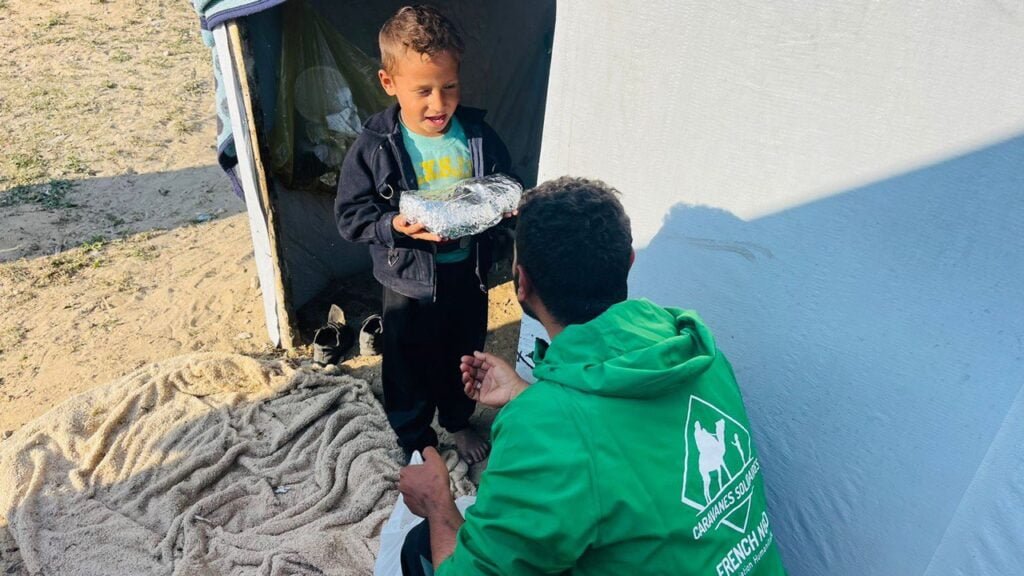 Photo d'un enfant qui reçoit un repas lors de nos distributions dans les camps de réfugiés à Rafah