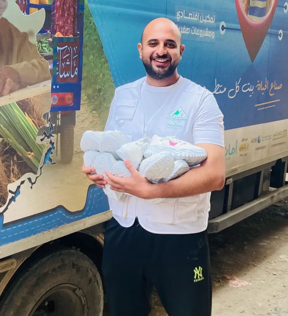 Membre ONG Caravanes solidaires avec des chaussures dans les bras