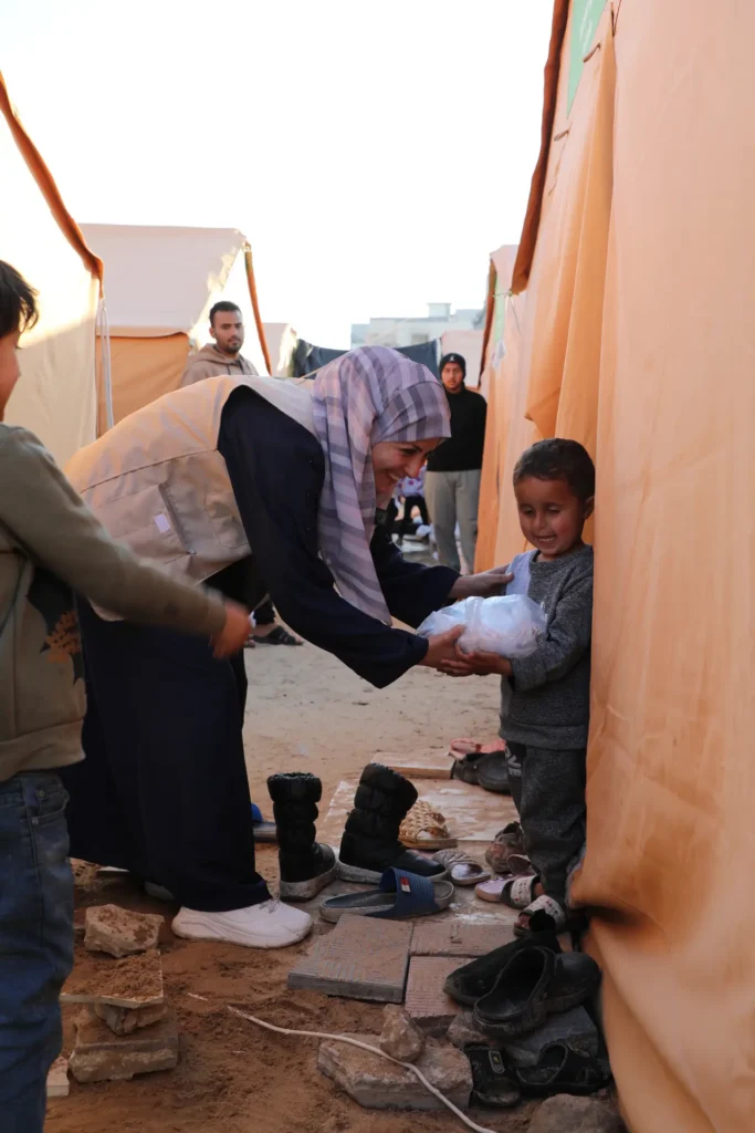 Responsable Caravanes Solidaires donne un paquet à un enfant qui sourit